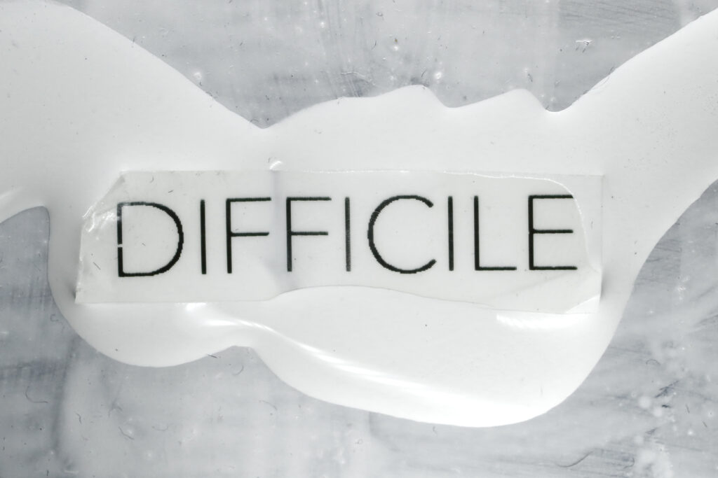 Mot « DIFFICILE » inscrit sur une surface blanche — photographie de Richard Schlang