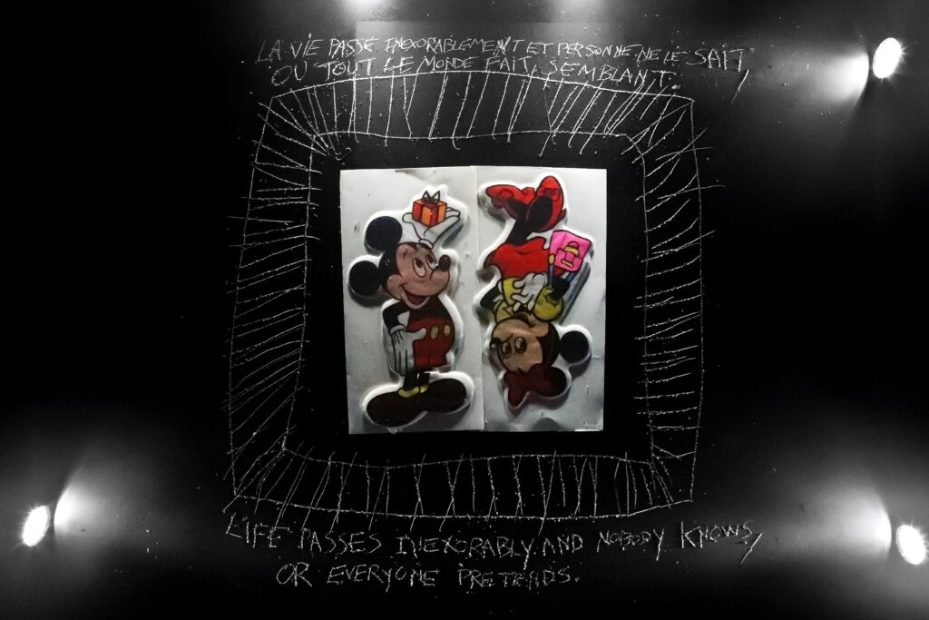 Personnages de Mickey et Minnie Mouse photographiés sur un fond noir, entourés de dessins et de phrases manuscrites — photographie de Richard Schlang
